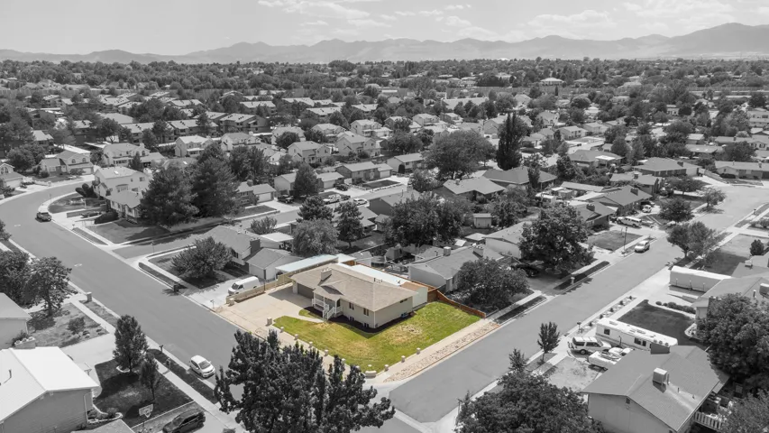 Property situated on a corner lot featuring mature trees, a driveway, and a fenced yard