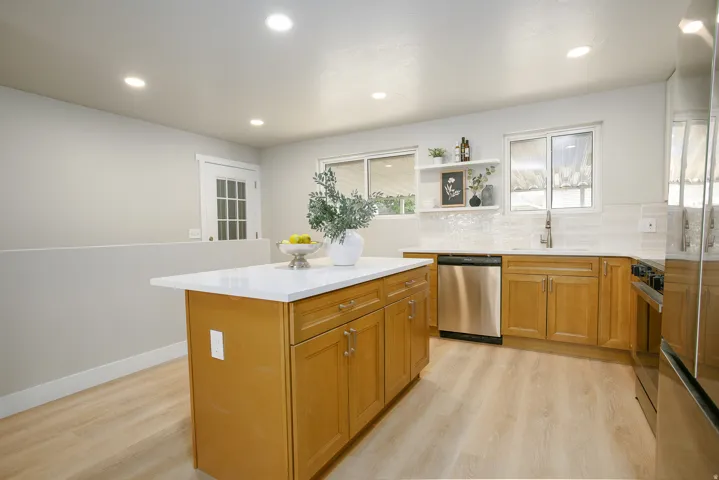 Kitchen featuring light wood-finish cabinetry, a central island with a white countertop, recessed lighting, and stainless steel appliances