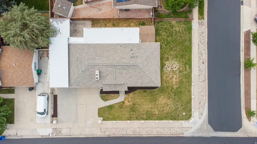 Gable roof with central chimney, concrete driveway, front walkway, and perimeter landscaping