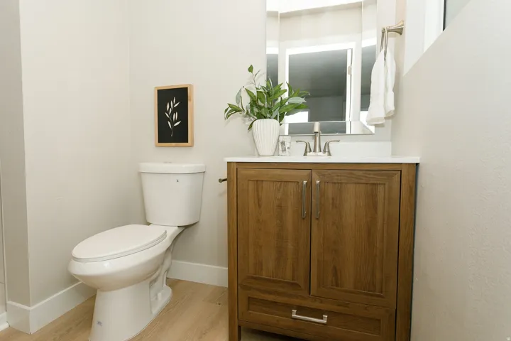 Wood-finish vanity with a white countertop and rectangular mirror