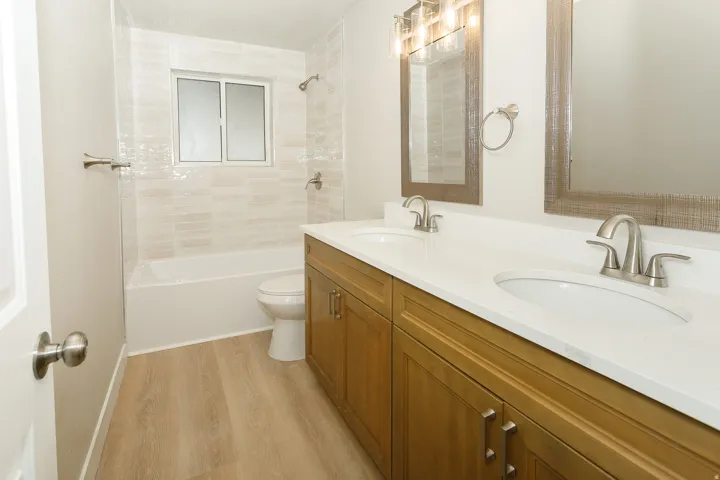 Dual vanity with white undermount sinks, wood-finish cabinetry, and brushed nickel fixtures
