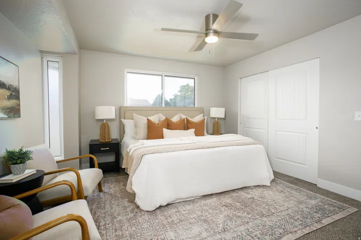 Light gray wall paint, a window with a white frame, a ceiling fan with integrated lighting, and white sliding closet doors
