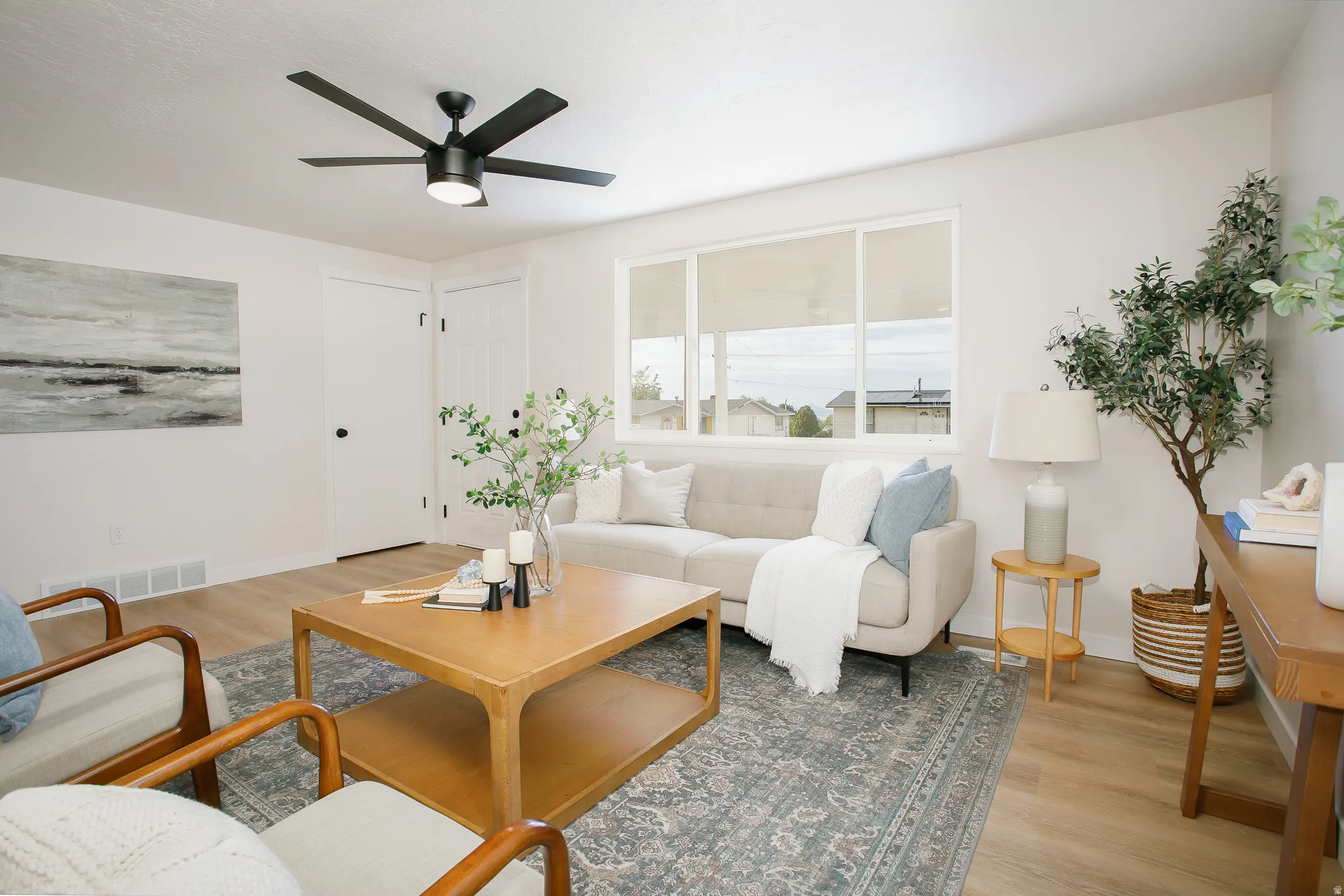 Bright living space with wood-finish flooring, a contemporary ceiling fan, and large windows
