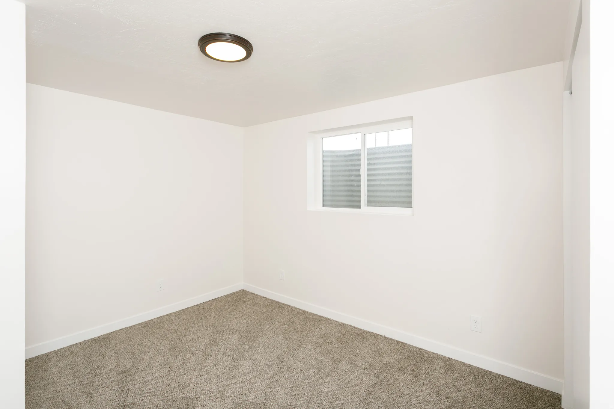 Neutral wall paint, carpeted flooring, and a single window with blinds