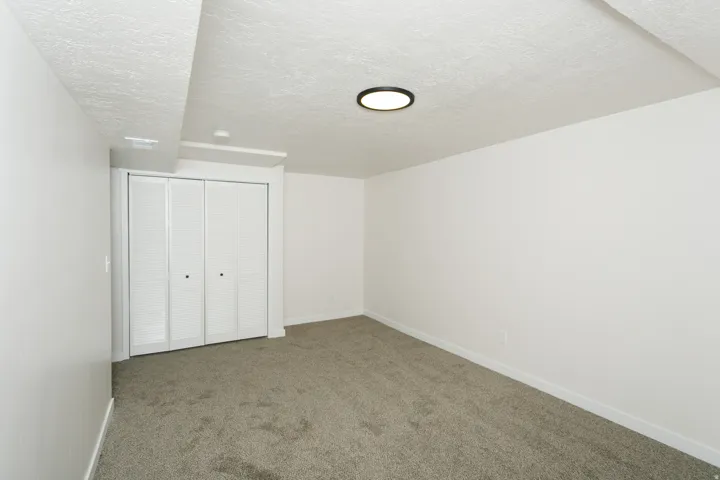 Neutral-toned carpeting and white walls with a built-in closet featuring bi-fold louvered doors