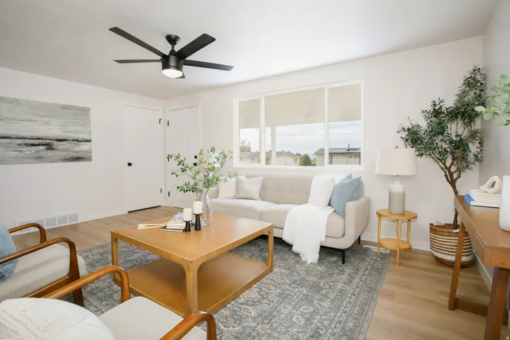 Bright living space with wood-finish flooring, a contemporary ceiling fan, and large windows