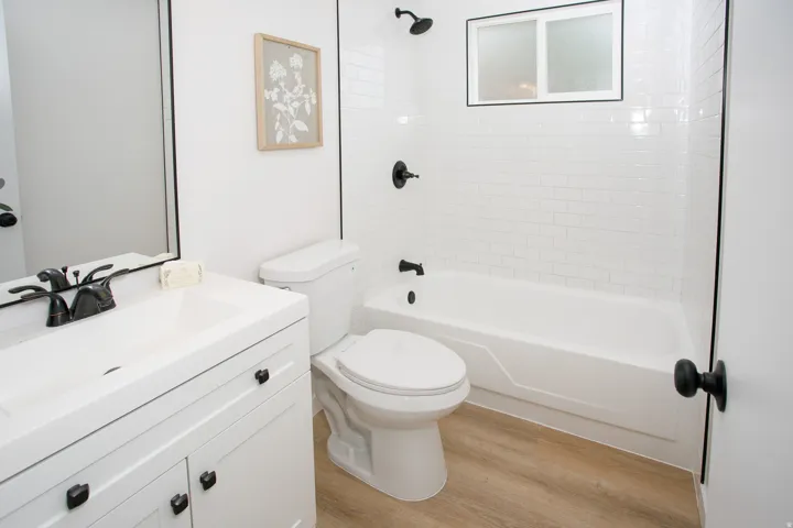 White vanity with a rectangular integrated sink, black-finish faucet, and coordinating black hardware