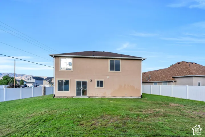 Rear exterior featuring stucco siding, sliding glass door, and multiple windows