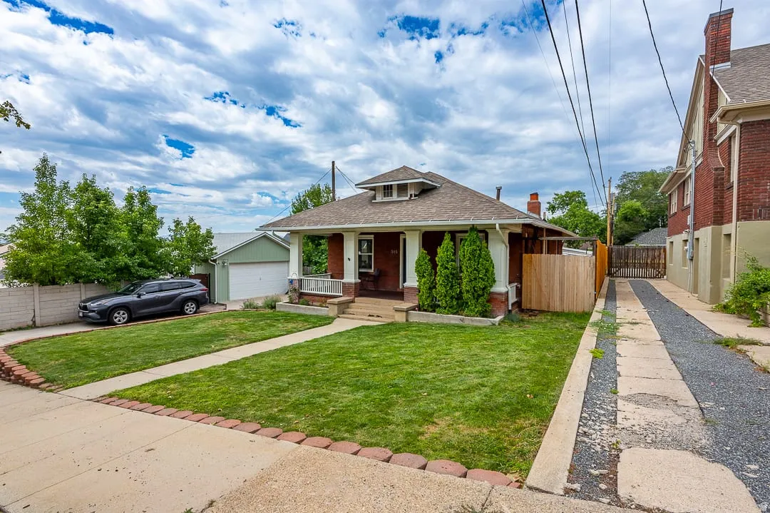 Brick exterior with a covered porch, detached garage, and a fenced yard