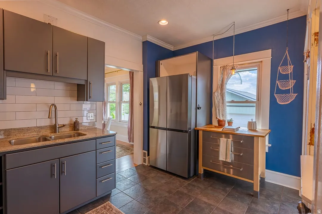 Stainless steel refrigerator, gray cabinetry, subway tile backsplash, light-toned granite countertop, and dark-toned tile flooring