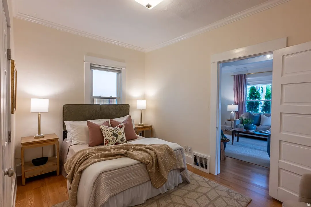 Hardwood flooring, crown molding, white trim work, and a single window
