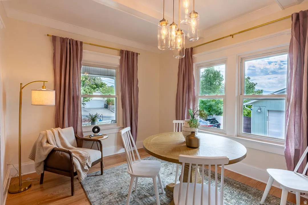 Hardwood-style flooring, white trim, crown molding, coffered ceiling detail, and a multi-light pendant fixture