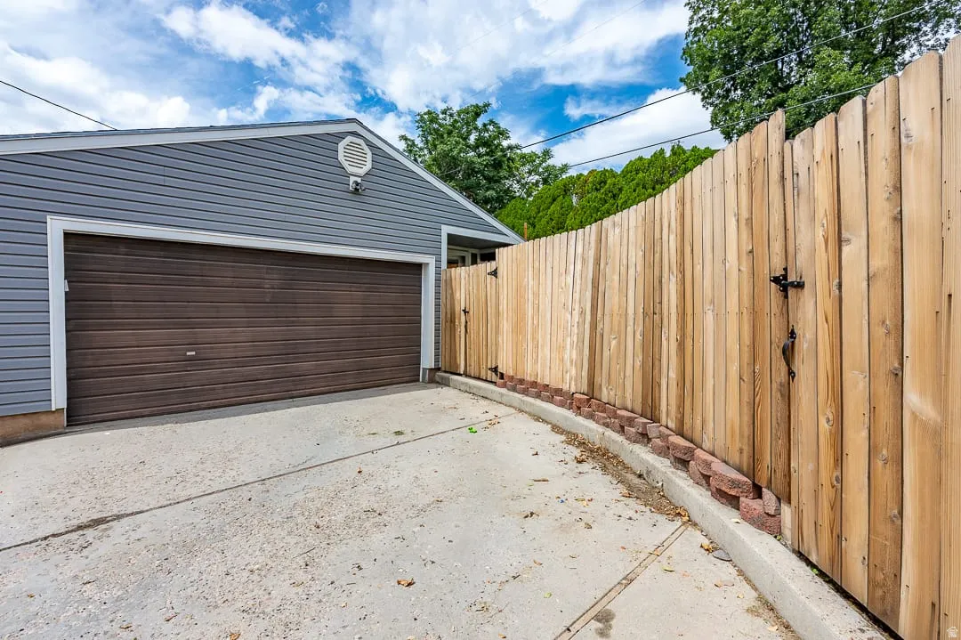 Detached garage with horizontal siding, a paneled garage door, and a decorative gable vent