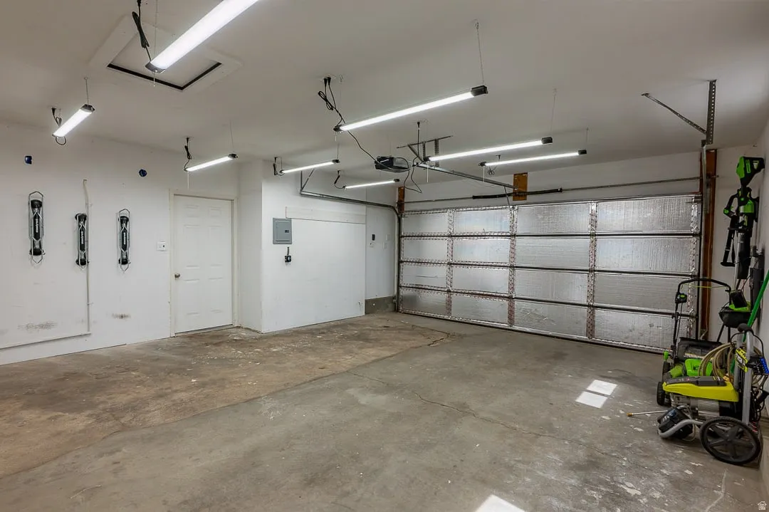 Spacious garage with multiple overhead LED light fixtures, and an insulated garage door