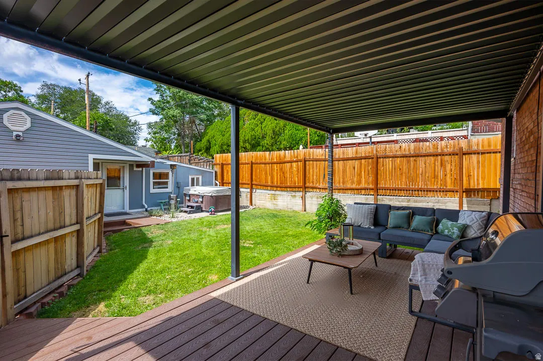 Expansive wood-finish deck with a solid overhead patio cover, surrounded by a wood privacy fence and green lawn