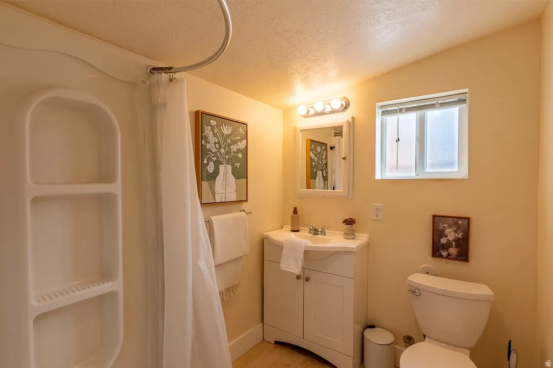 Bathroom featuring a shower stall with built-in shelving, a white vanity with a basin sink, a wall-mounted medicine cabinet, and an overhead light fixture