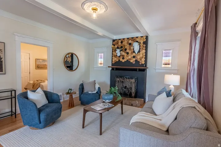 Living area featuring a fireplace with a dark-toned mantel, light-toned walls, wood-finish flooring, and a decorative ceiling medallion