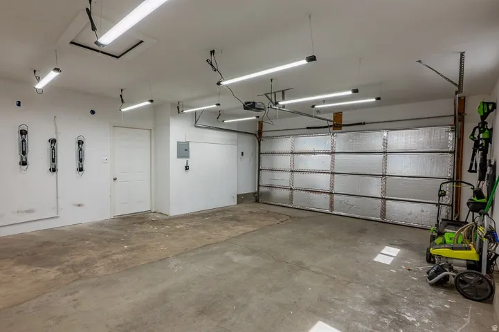 Spacious garage with multiple overhead LED light fixtures, and an insulated garage door