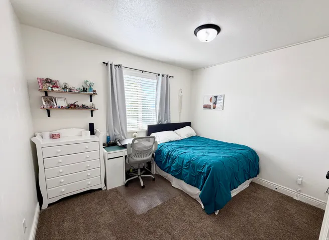 Recessed window with blinds, overhead flush mount lighting, and wood-finish wall shelving