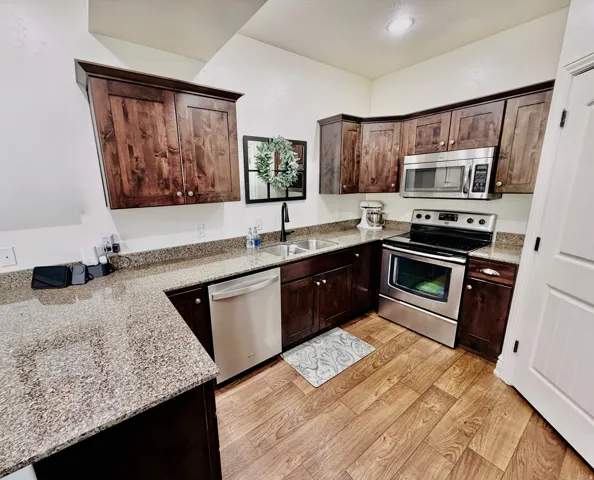 Full kitchen featuring wood-finish flooring, dark wood cabinetry, and stainless steel appliances