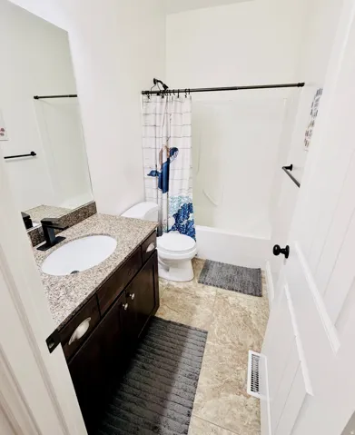 Full bathroom featuring a single vanity with a granite countertop, a built-in sink, dark wood-finish cabinetry, and a shower-tub combination