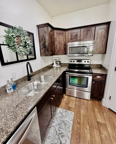 Dark wood cabinetry with stone countertops, a stainless steel range, and a stainless steel over-the-range microwave