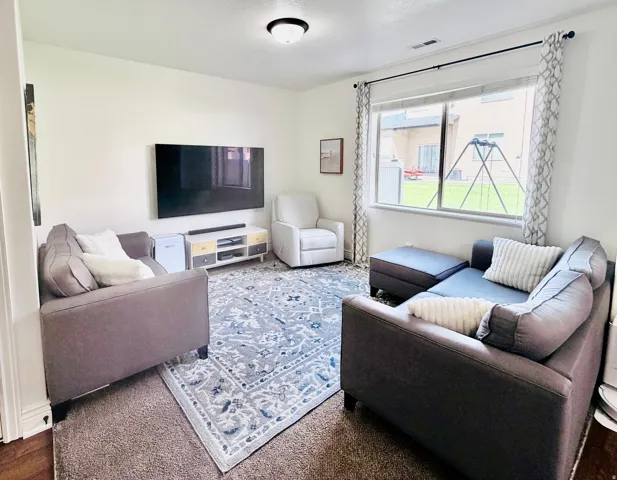 Recessed lighting illuminates this bright room featuring a large window, light-colored walls, and dark wood-finish flooring