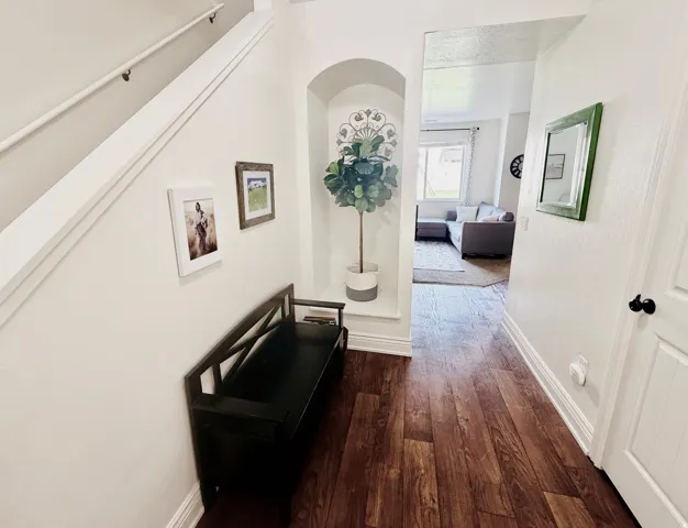 Hardwood-style flooring throughout, featuring a built-in arched alcove and white painted baseboards