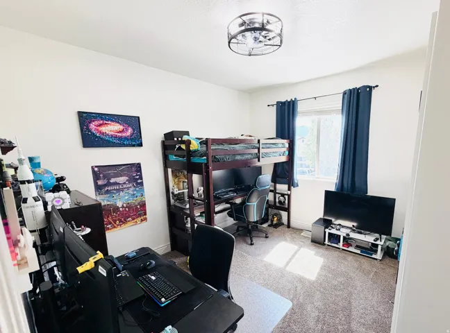 Carpeted room featuring a ceiling-mounted light fixture and a window with a curtain rod