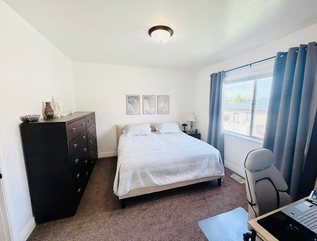White walls, textured carpeting, and a window with a dark curtain rod