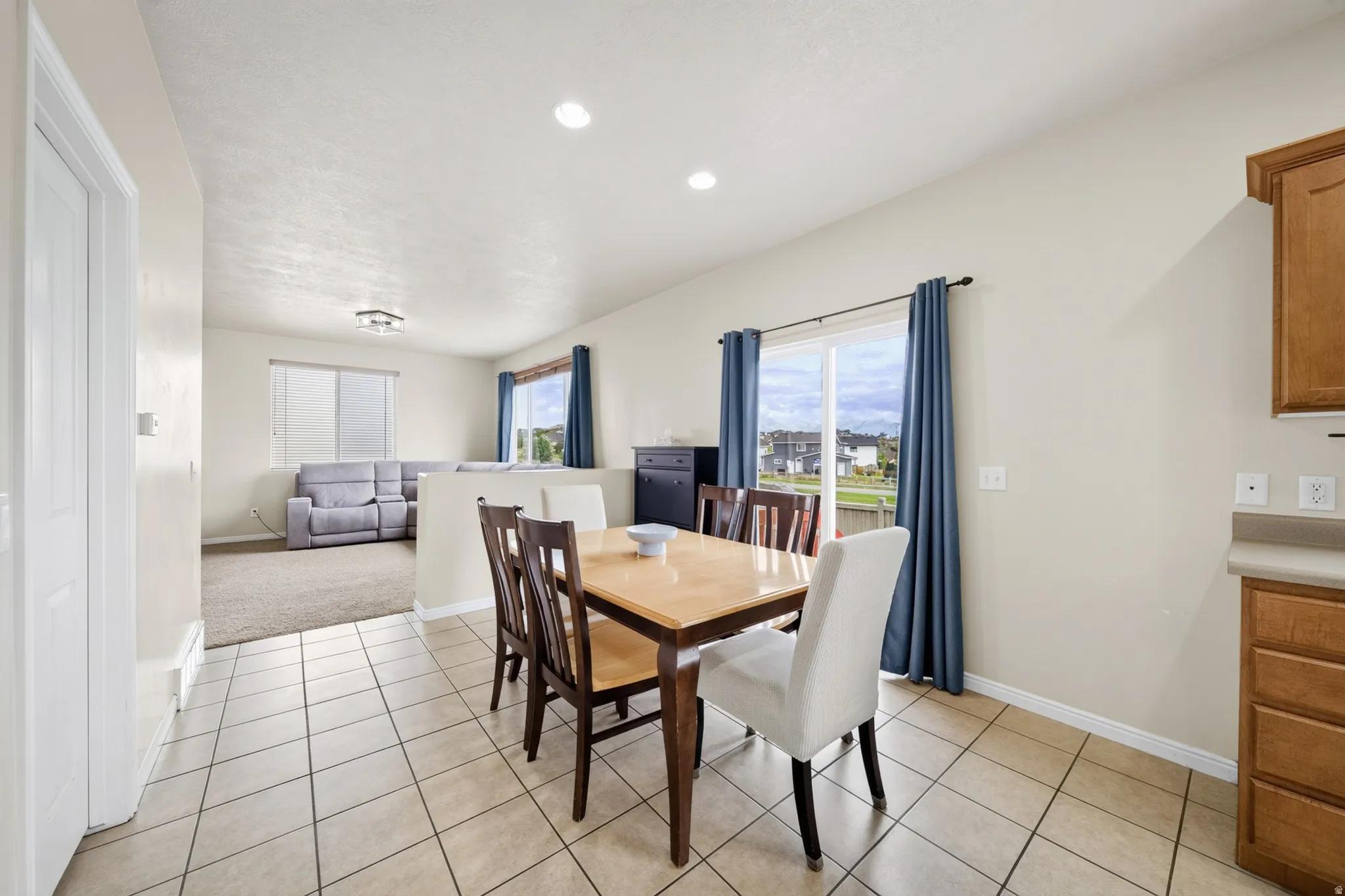 Tiled flooring in the dining area with a sliding glass door, recessed lighting, and wood cabinetry with a laminate countertop