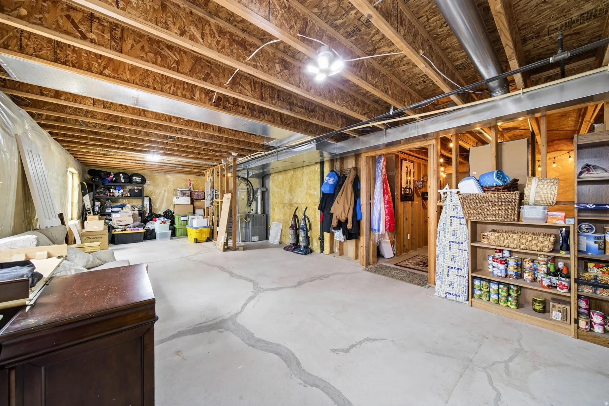 Unfinished basement featuring exposed wood joists and concrete flooring