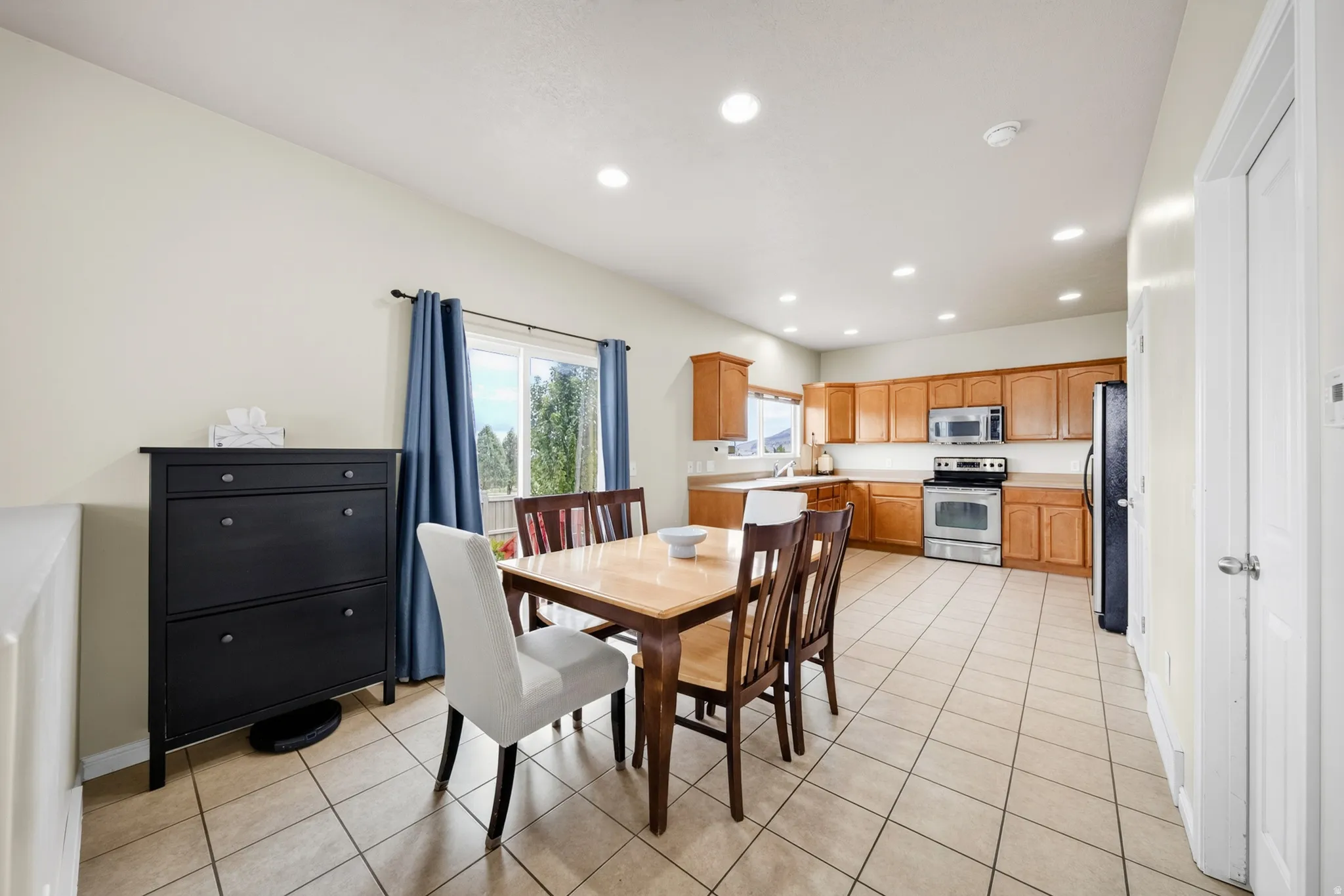 Kitchen with light wood-finish cabinetry, stainless steel appliances, and tile flooring