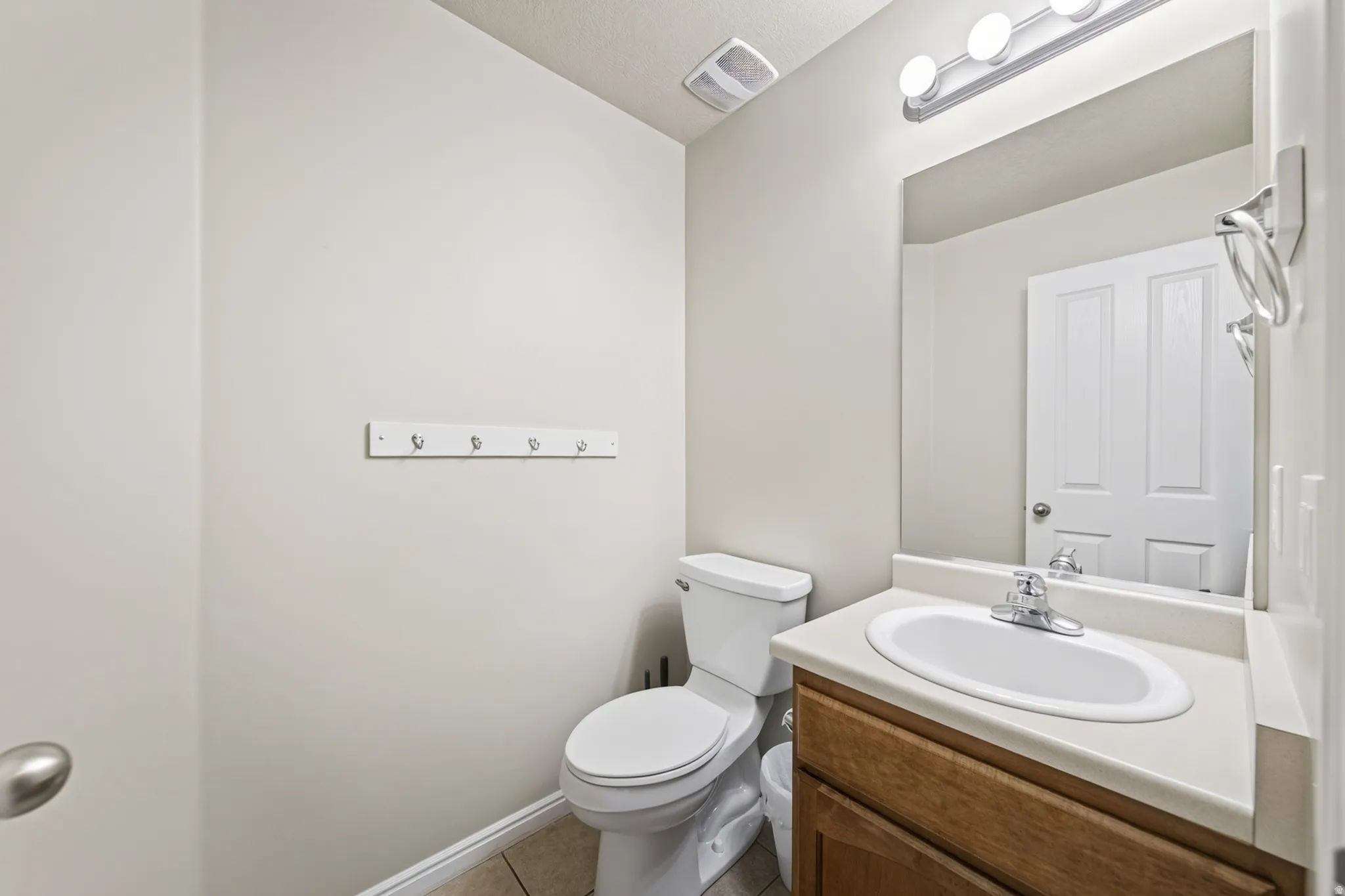 Bathroom featuring a single vanity with wood-finish cabinetry, an oval undermount sink, and a light-toned countertop