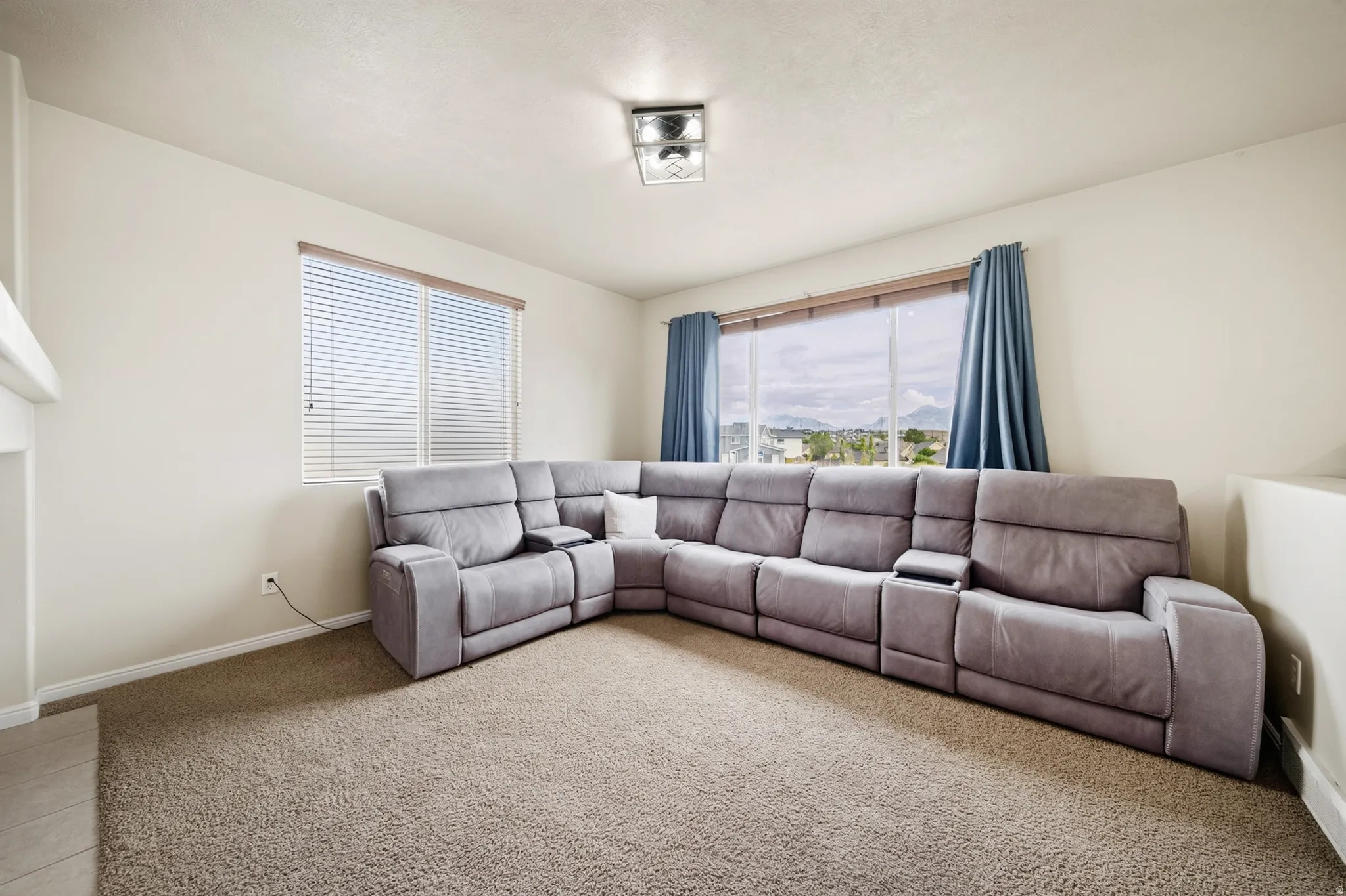 Recessed lighting with a contemporary flush-mount fixture, carpeted flooring, and multiple windows offering natural light