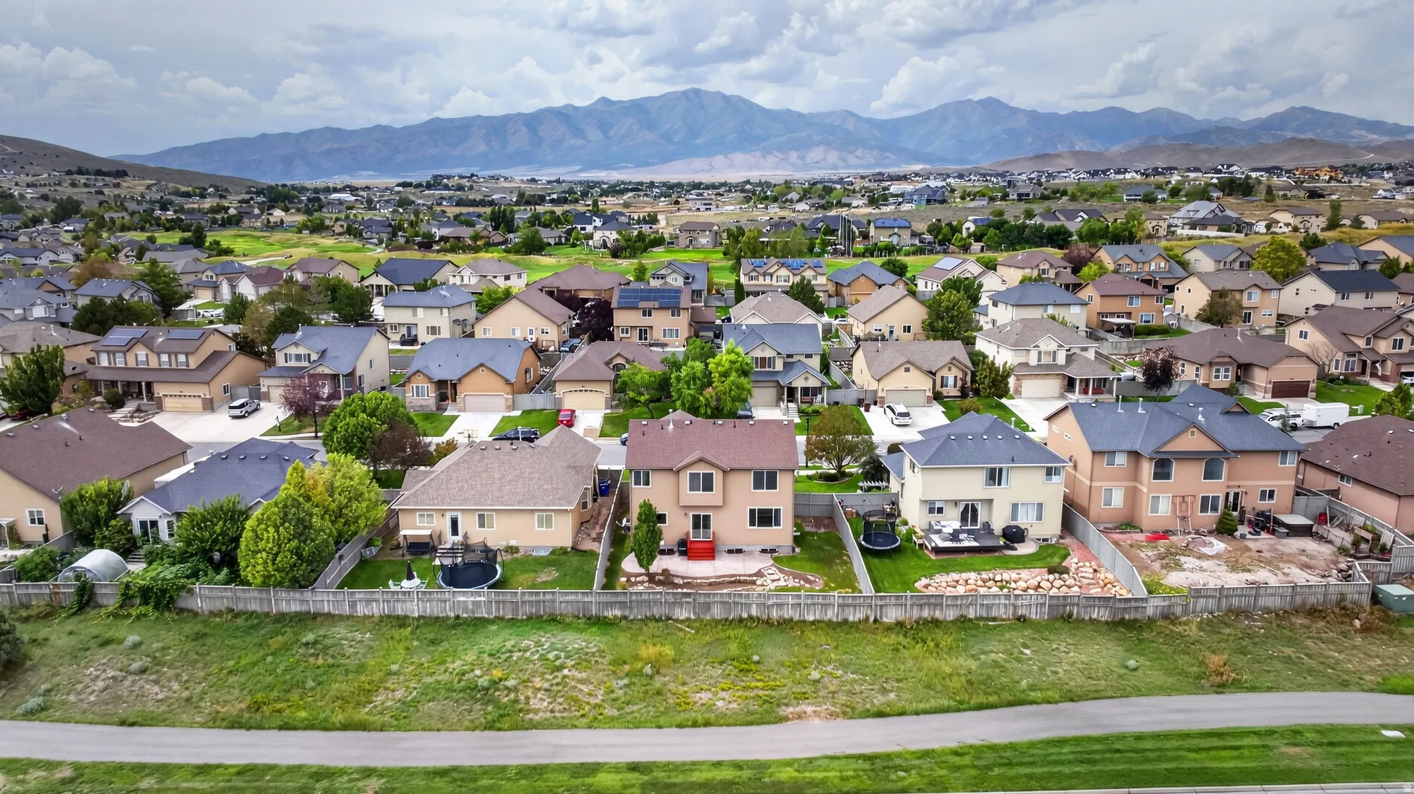 Residential neighborhood with diverse home styles, fenced backyards, and distant mountain scenery
