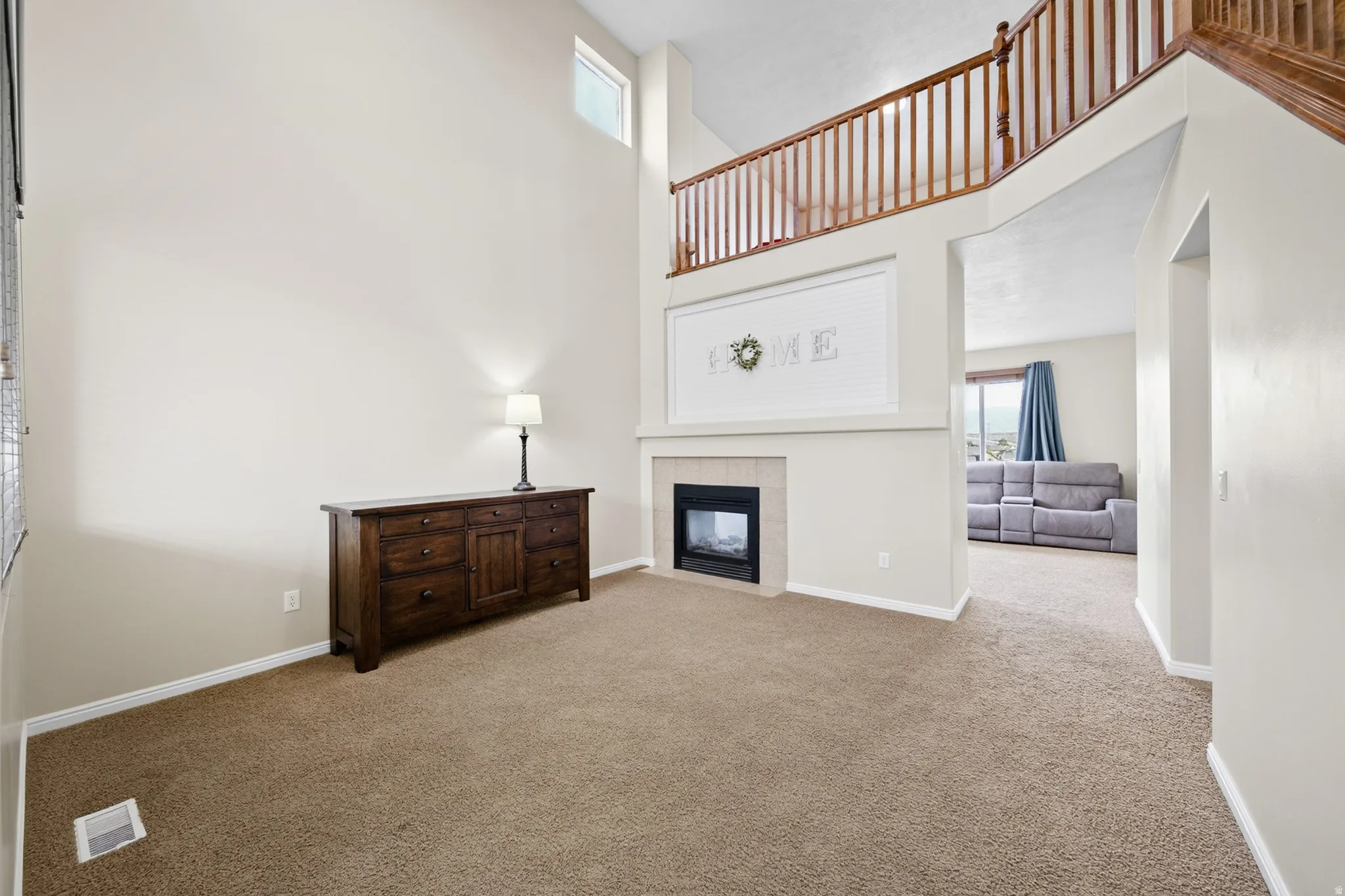 Vaulted ceiling with transom window, gas fireplace with hearth, and an open stairwell with wood railing