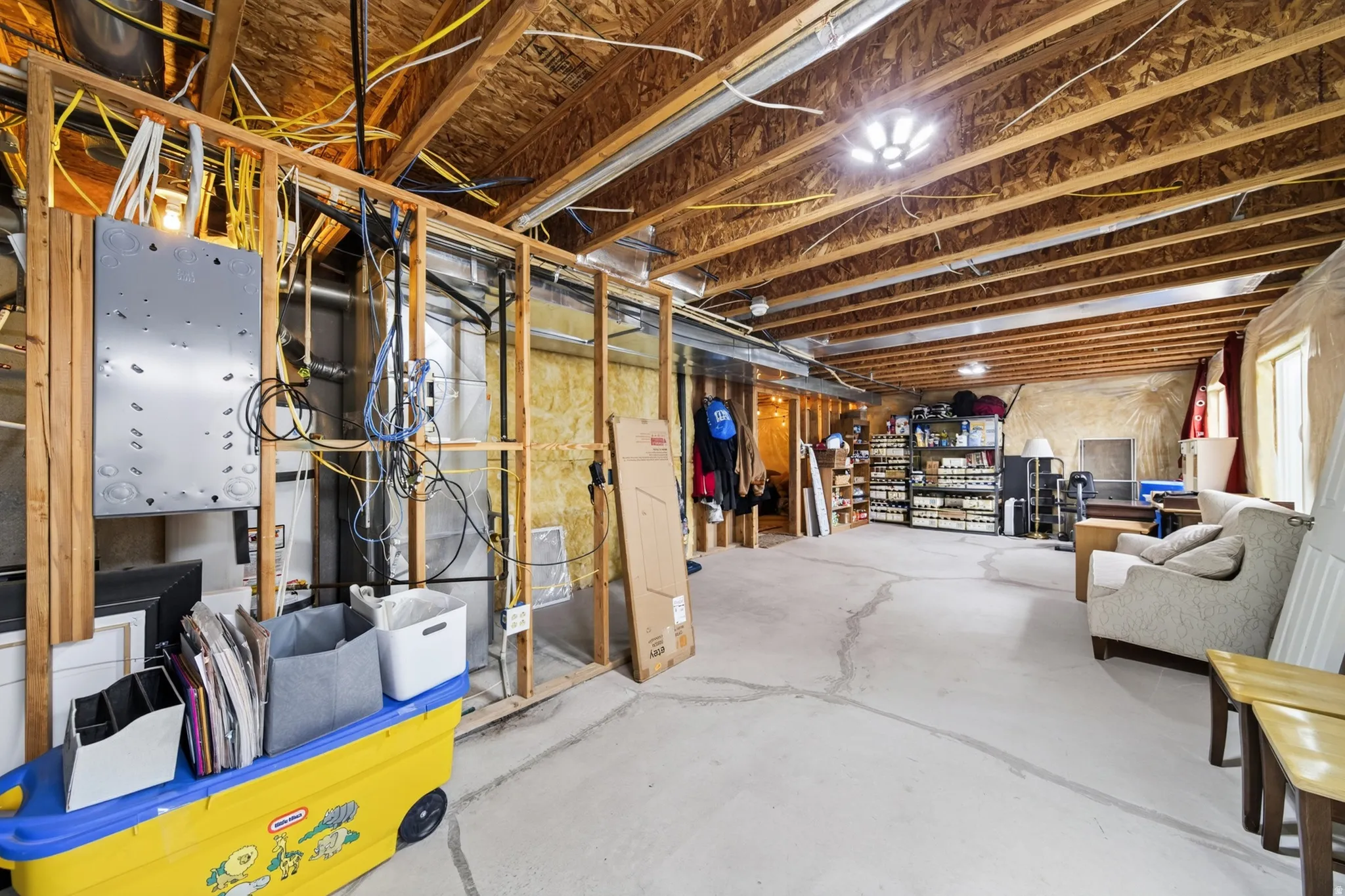 Unfinished basement with exposed wood framing, concrete flooring, and visible ceiling joists