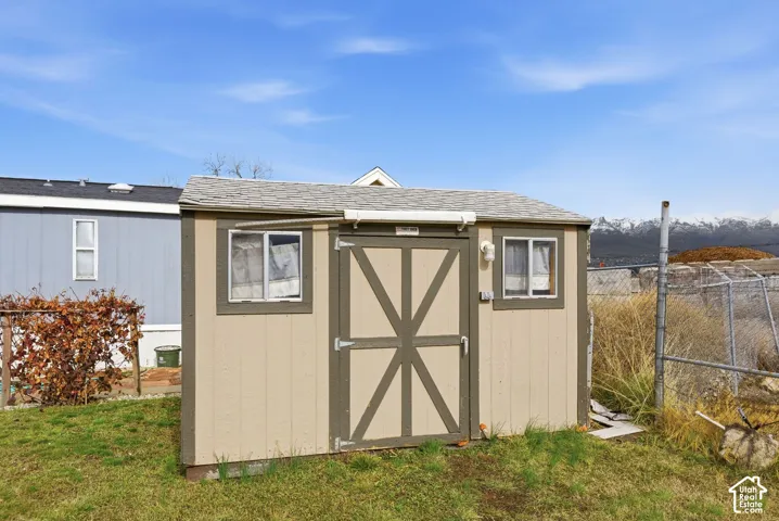 Detached storage shed with two windows, a single entry door, and a shingled roof