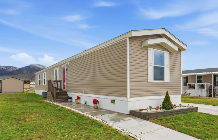 Siding exterior with decorative shutters, front entry with wood steps, concrete walkway, and a raised garden bed