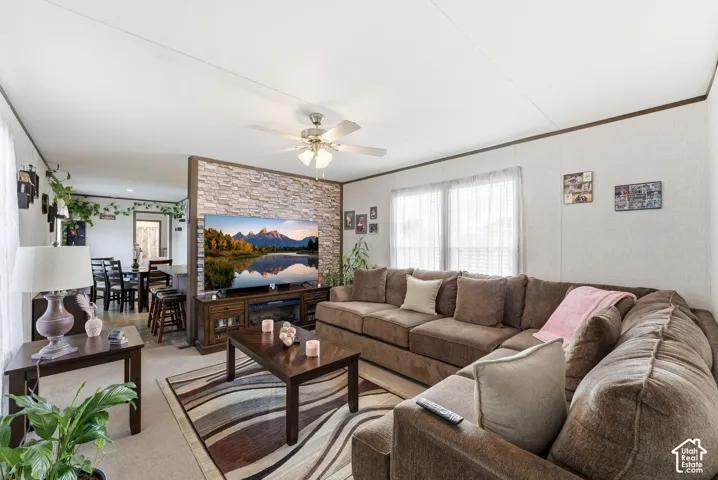 Open-concept living area featuring a stone-accented media wall, ceiling fan, and carpeted flooring