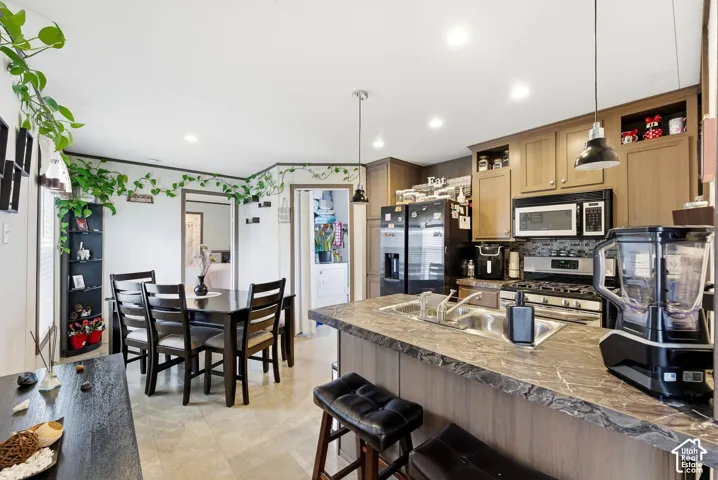 Kitchen featuring wood-finish cabinetry, stainless steel appliances, stone-look countertops, and a tile backsplash