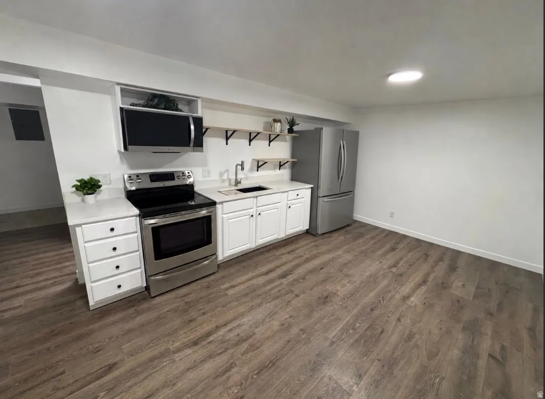 Updated kitchen featuring white shaker-style cabinetry, stainless steel appliances, wood-finish flooring, and recessed lighting