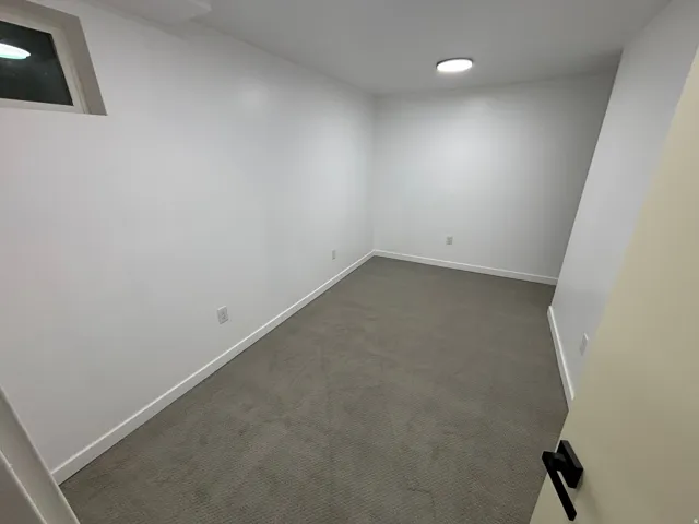 Recessed ceiling light, neutral wall paint, gray carpet, white trim, and a window