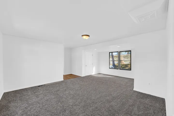 Spacious room with gray carpet, white walls, and black-framed windows