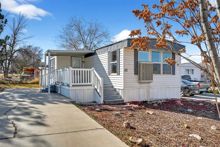 White exterior siding with dark shutters, covered front porch, and a concrete driveway