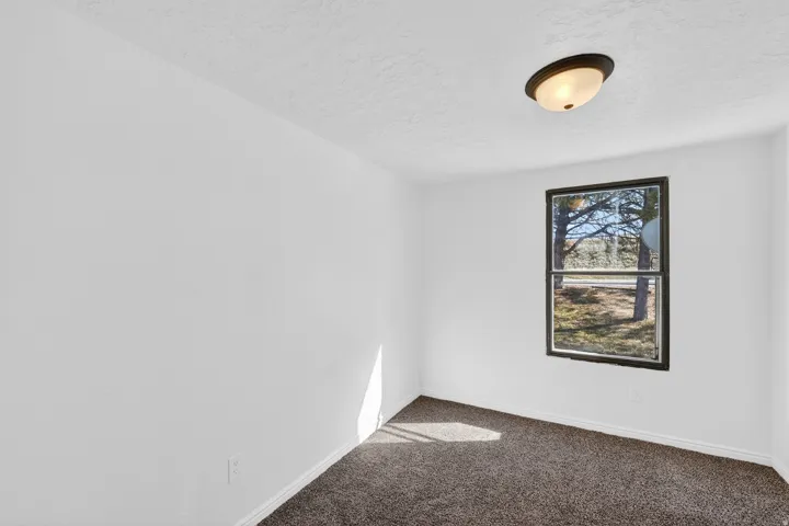 White painted walls with a single window and ceiling-mounted light fixture