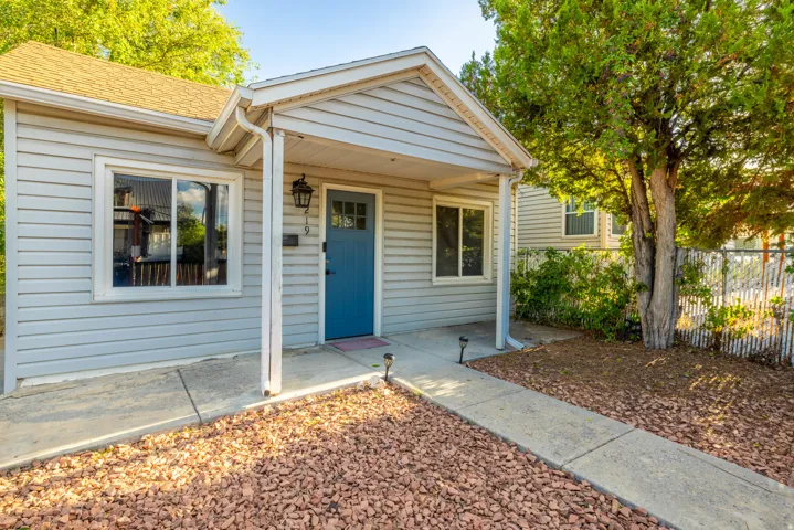 Light gray siding exterior with a bright blue front door, covered porch entry, and a concrete walkway
