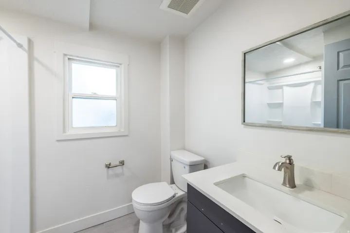 Bathroom featuring a single window, white walls, and a vanity with a white countertop and undermount sink