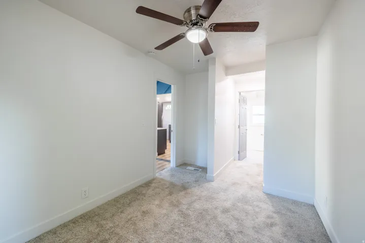 Neutral paint palette with ceiling fan, carpeted flooring, and white trim